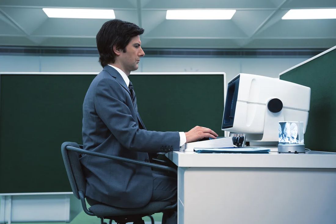 un impiegato di spalle davanti a un monitor in un ufficio